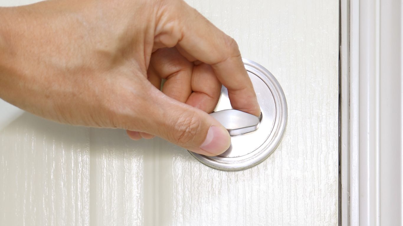 Hand turning a deadbolt on the inside of a Melbourne residential front door.